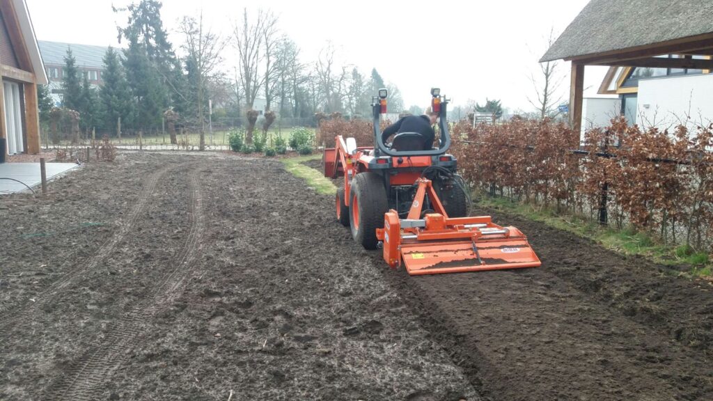 Traktor mit Bodenfräse lockert den Boden auf, um eine optimale Grundlage für die Verlegung von Rollrasen zu schaffen. Die Bodenbearbeitung verbessert die Durchlässigkeit und Nährstoffaufnahme.