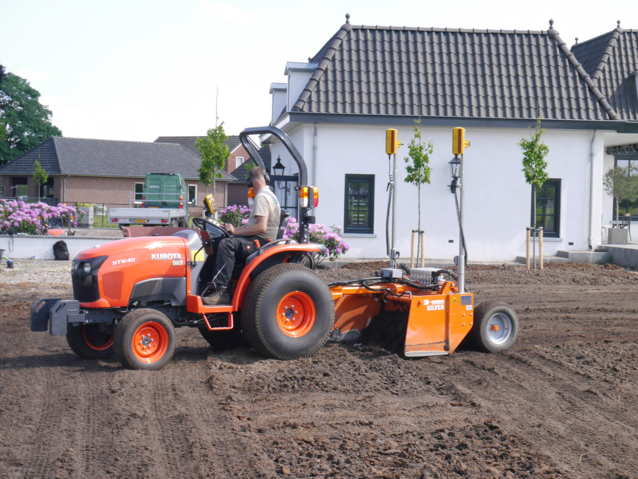 Traktor mit lasergesteuerter Nivelliermaschine ebnet den Boden für eine gleichmäßige und stabile Fläche. Diese Technik sorgt für eine optimale Vorbereitung der Rasenverlegung.