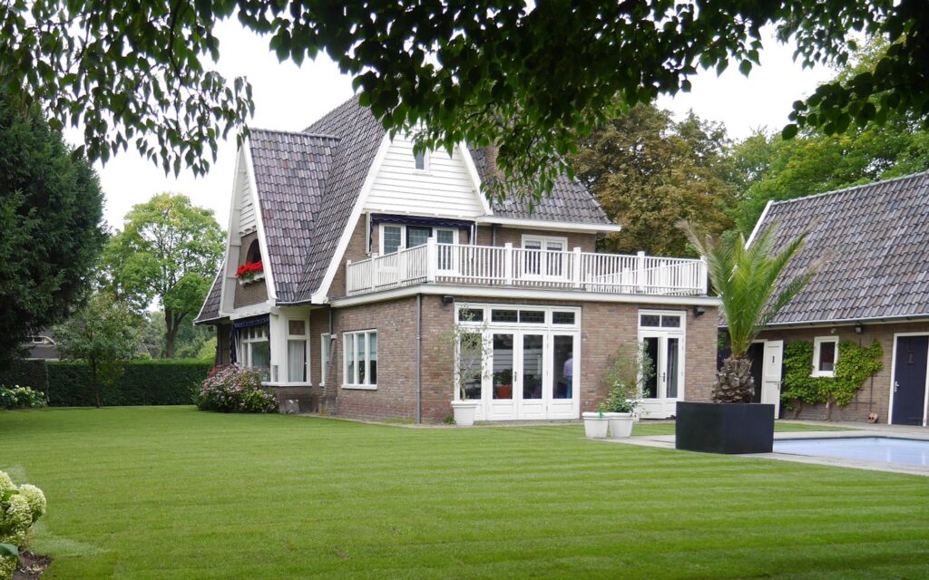 Rollrasen der um ein ganzes Haus verläuft. Daneben befinden sich ein Pool und eine Palme